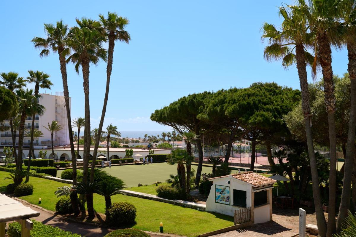 vistas a un parque con palmeras y a un edificio en Alua Illa de Menorca, en S'Algar