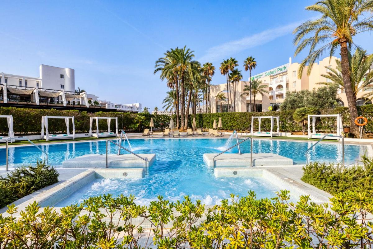 Una gran piscina con palmeras y edificios. en Protur Sa Coma Playa Hotel & Spa, en Sa Coma