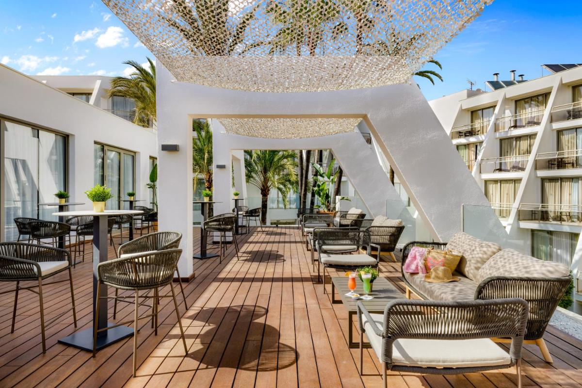 un patio al aire libre con sillas, mesas y una lámpara de araña en Protur Sa Coma Playa Hotel & Spa, en Sa Coma