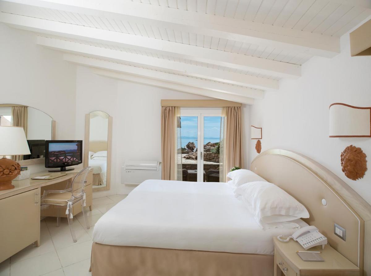 - une chambre blanche avec un lit, un bureau et une télévision dans l'établissement Hotel & SPA des Pecheurs, à Bonifacio