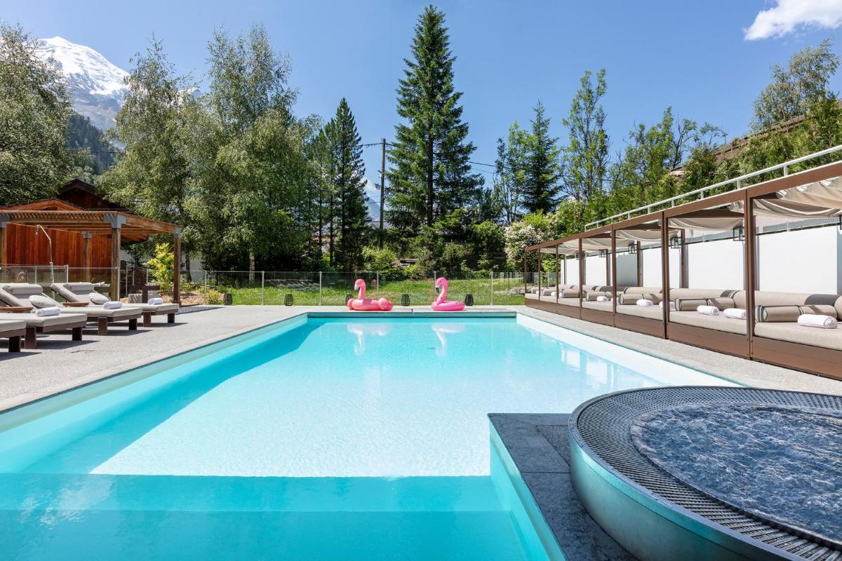 une piscine avec des chaises et une maison dans l'établissement Hôtel Les Aiglons Chamonix, à Chamonix-Mont-Blanc