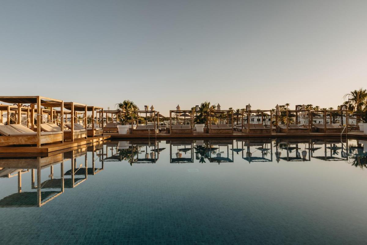 un complejo con mesas y sillas en el agua en Lago Resort Menorca - Casas del Lago Adults Only, en Cala'n Bosch