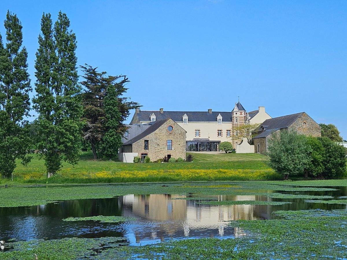 une grande maison avec un étang devant dans l'établissement Le Manoir de Kerbot, à Sarzeau