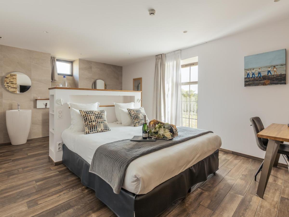 une chambre avec un grand lit et un bureau dans l'établissement Le Manoir de Kerbot, à Sarzeau