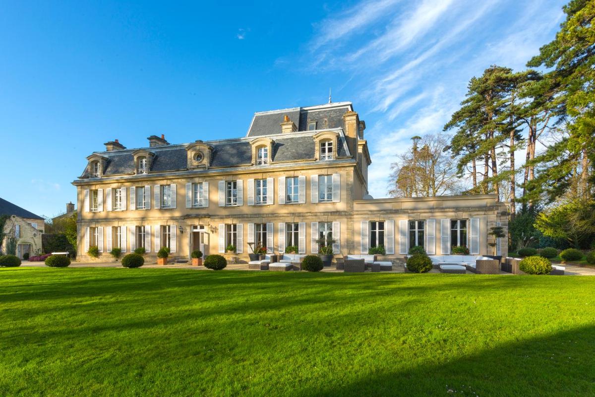 une grande maison sur un champ herbeux dans l'établissement Chateau La Cheneviere, à Port-en-Bessin-Huppain