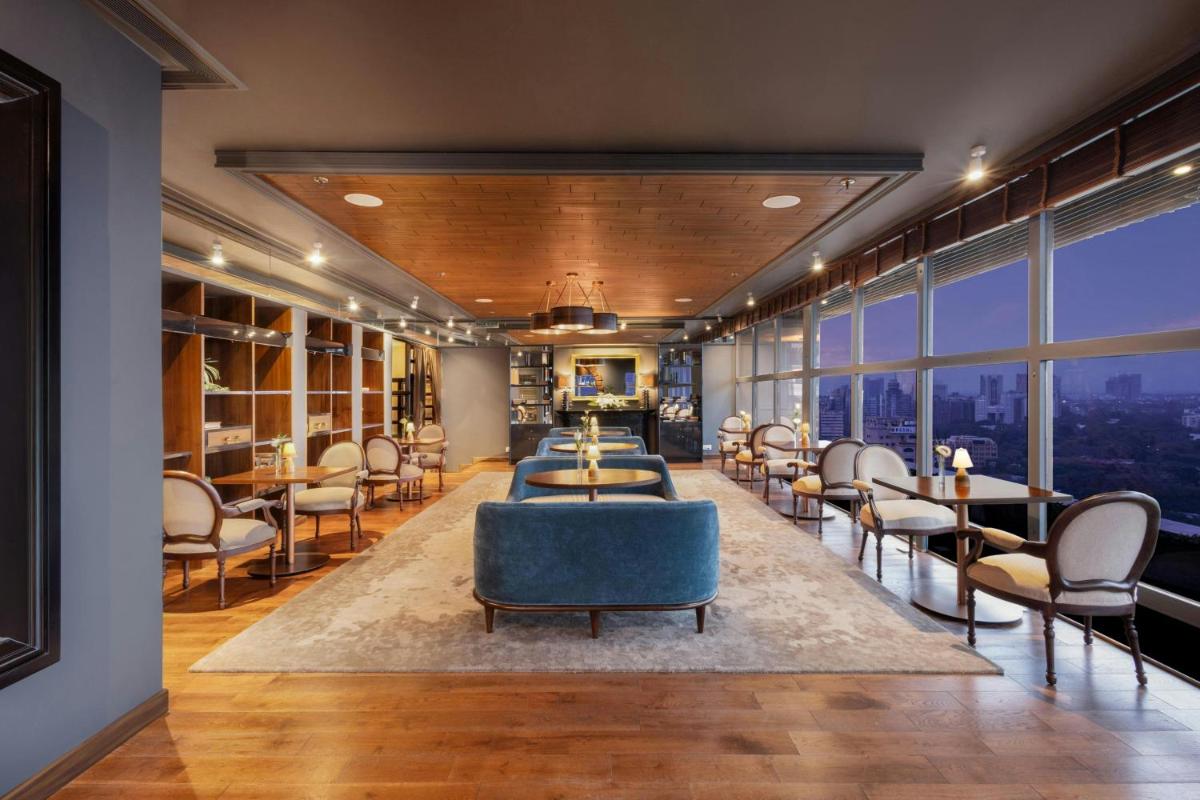 a waiting room with chairs and tables and windows at Le Meridien New Delhi in New Delhi a waiting room with chairs and tables and windows at Le Meridien New Delhi in New Delhi