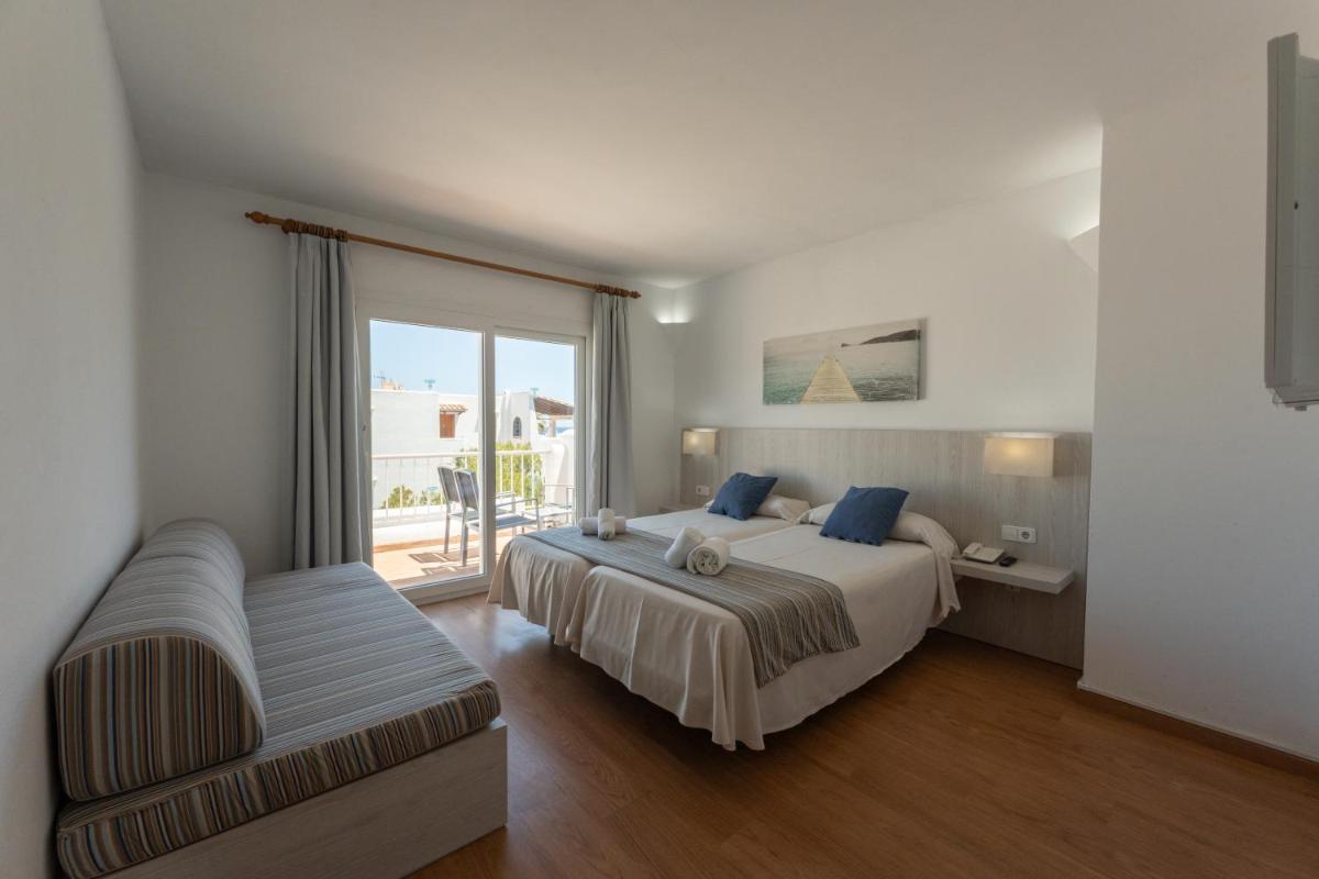 Un dormitorio con una cama y un sofá y una ventana. en Hotel Club Es Talaial, en Cala d´Or