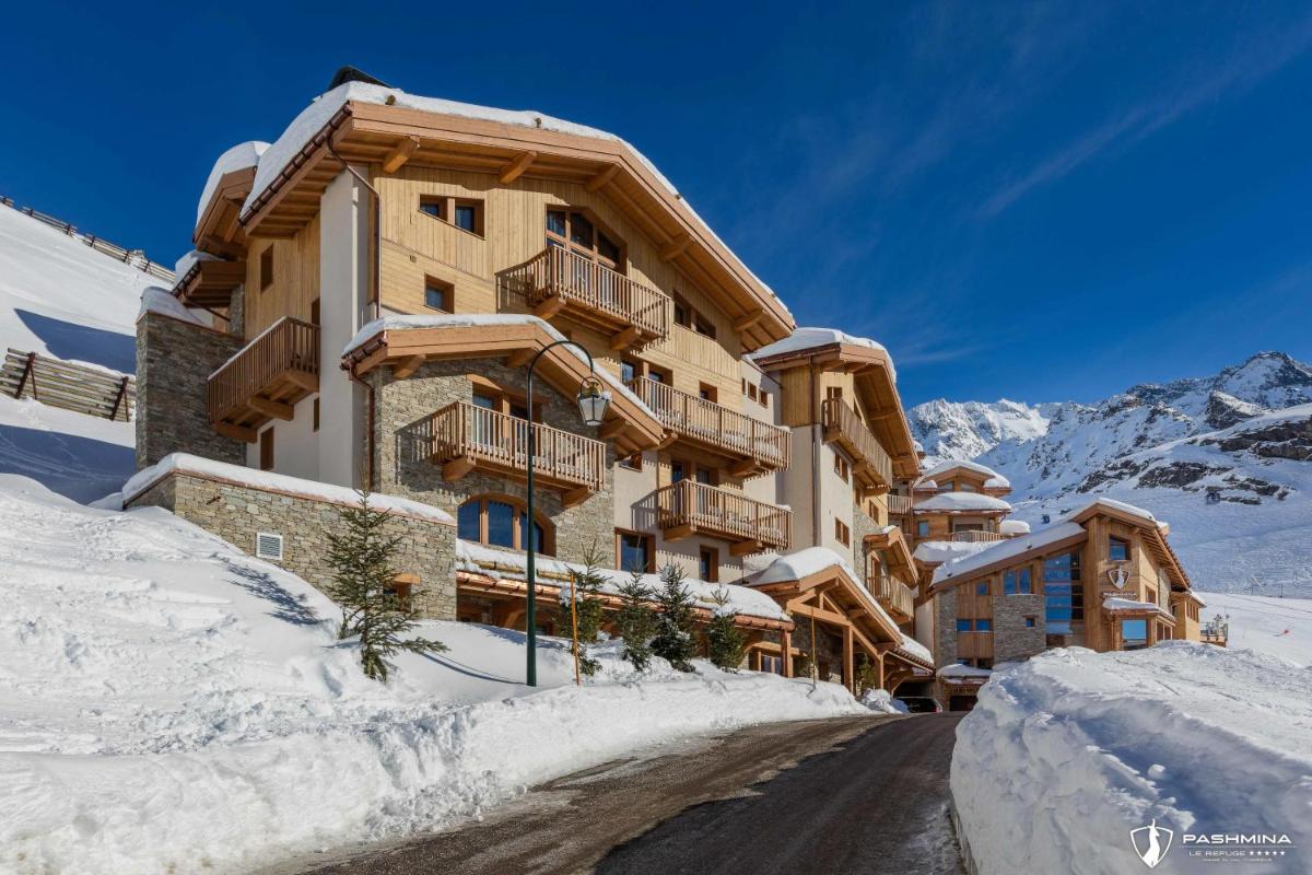 un bâtiment dans la neige avec une route devant dans l'établissement Hotel Pashmina Le Refuge, à Val Thorens