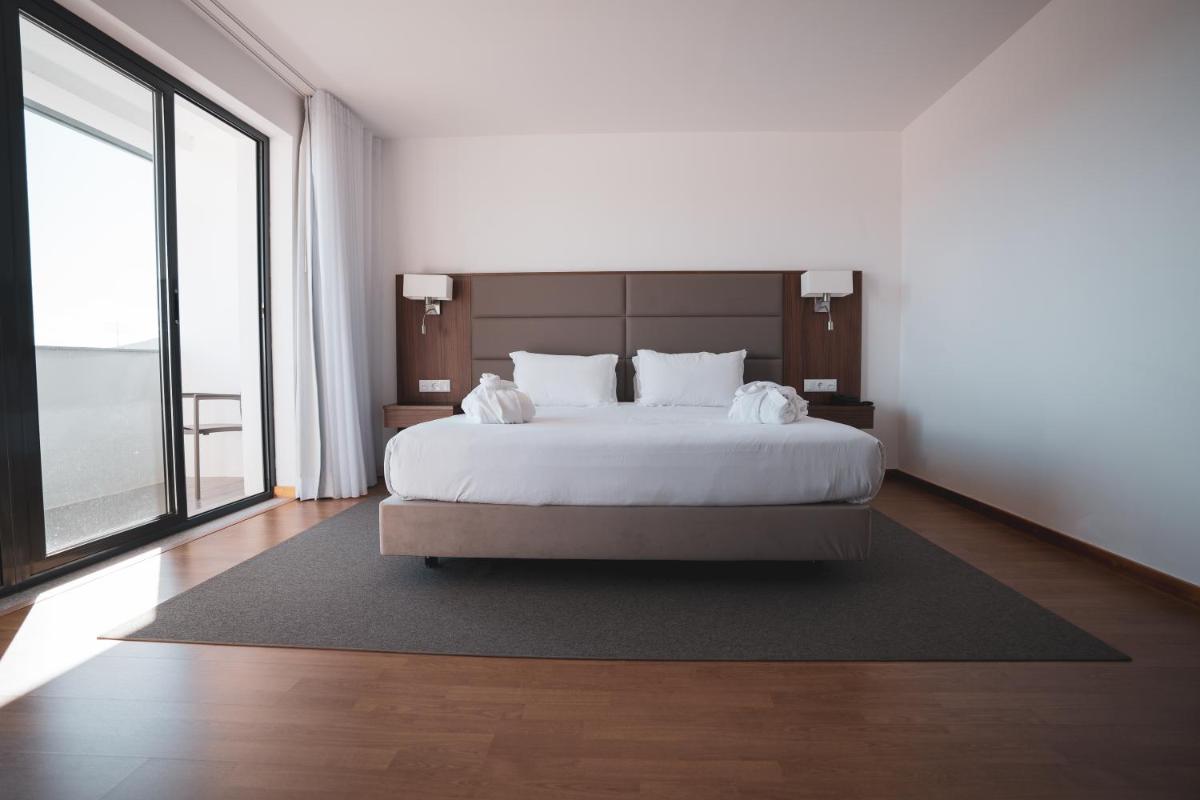 um quarto com uma cama grande e uma janela grande em Hotel Freixo Douro Superior em Freixo de Espada à Cinta