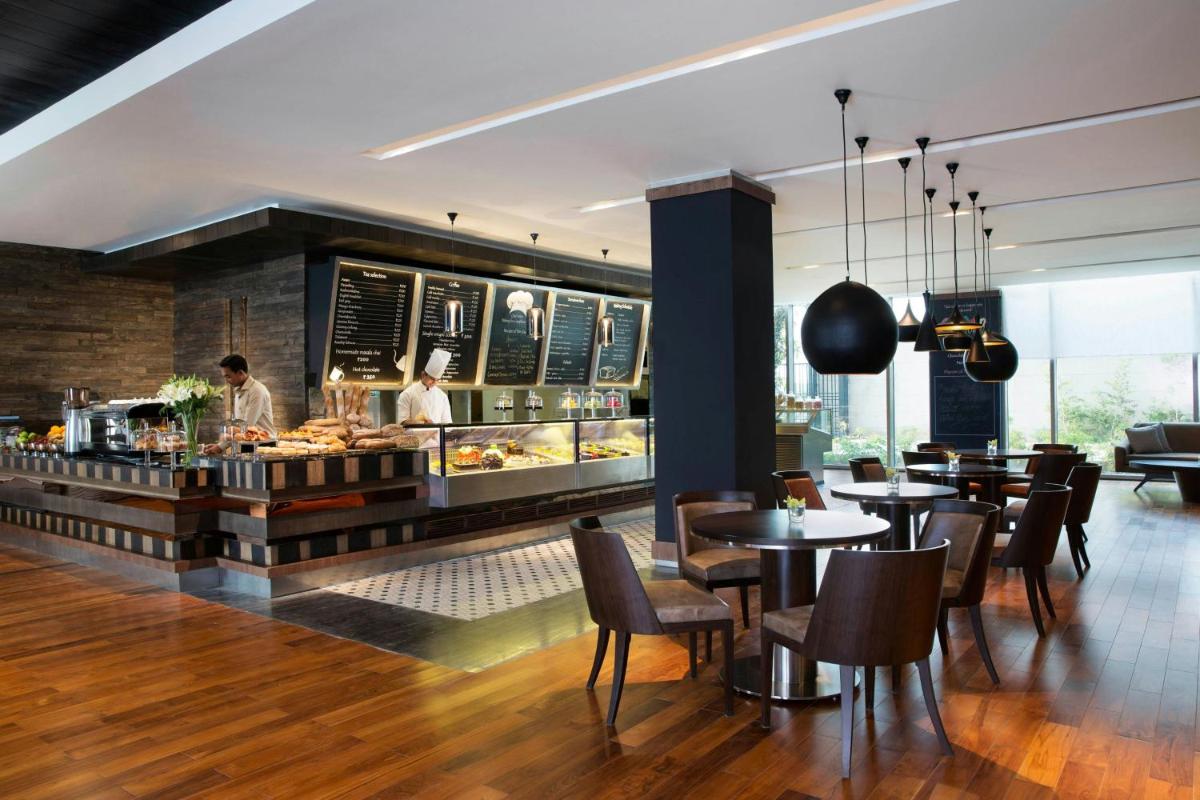 a restaurant with tables and people preparing food at JW Marriott Hotel New Delhi Aerocity in New Delhi a restaurant with tables and people preparing food at JW Marriott Hotel New Delhi Aerocity in New Delhi