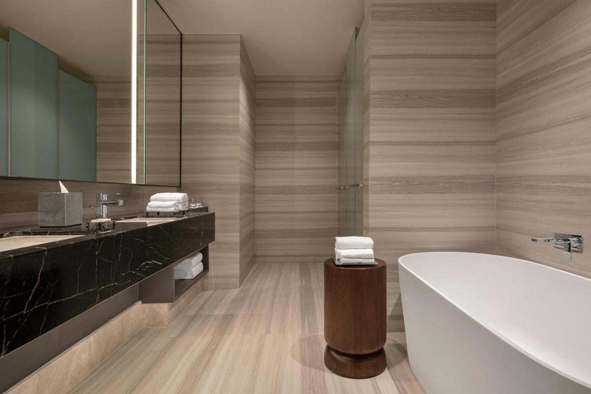 a bathroom with a tub and a large mirror at Bengaluru Marriott Hotel Whitefield in Bengaluru