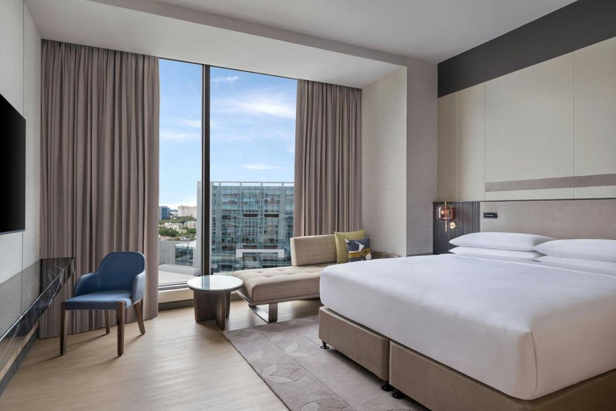 a hotel room with a bed and a large window at Bengaluru Marriott Hotel Whitefield in Bengaluru