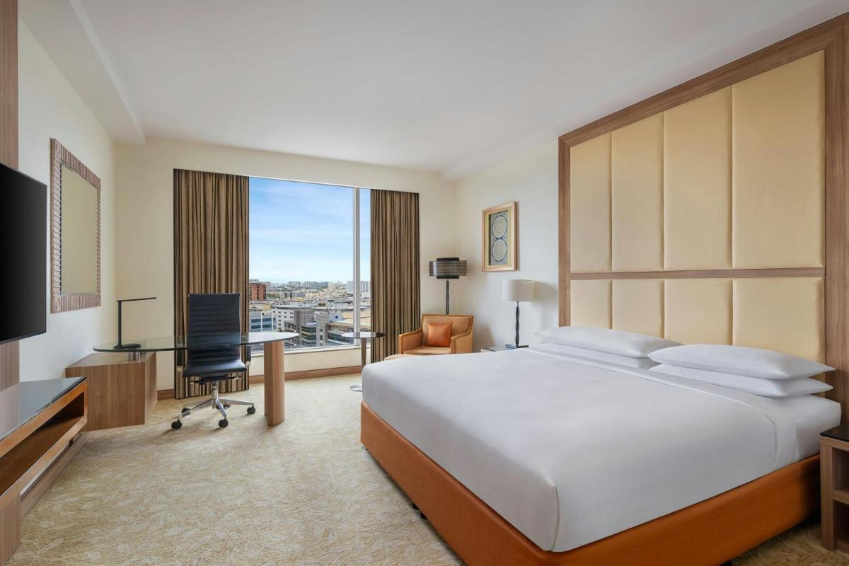 a hotel room with a large bed and a desk at Bengaluru Marriott Hotel Whitefield in Bengaluru