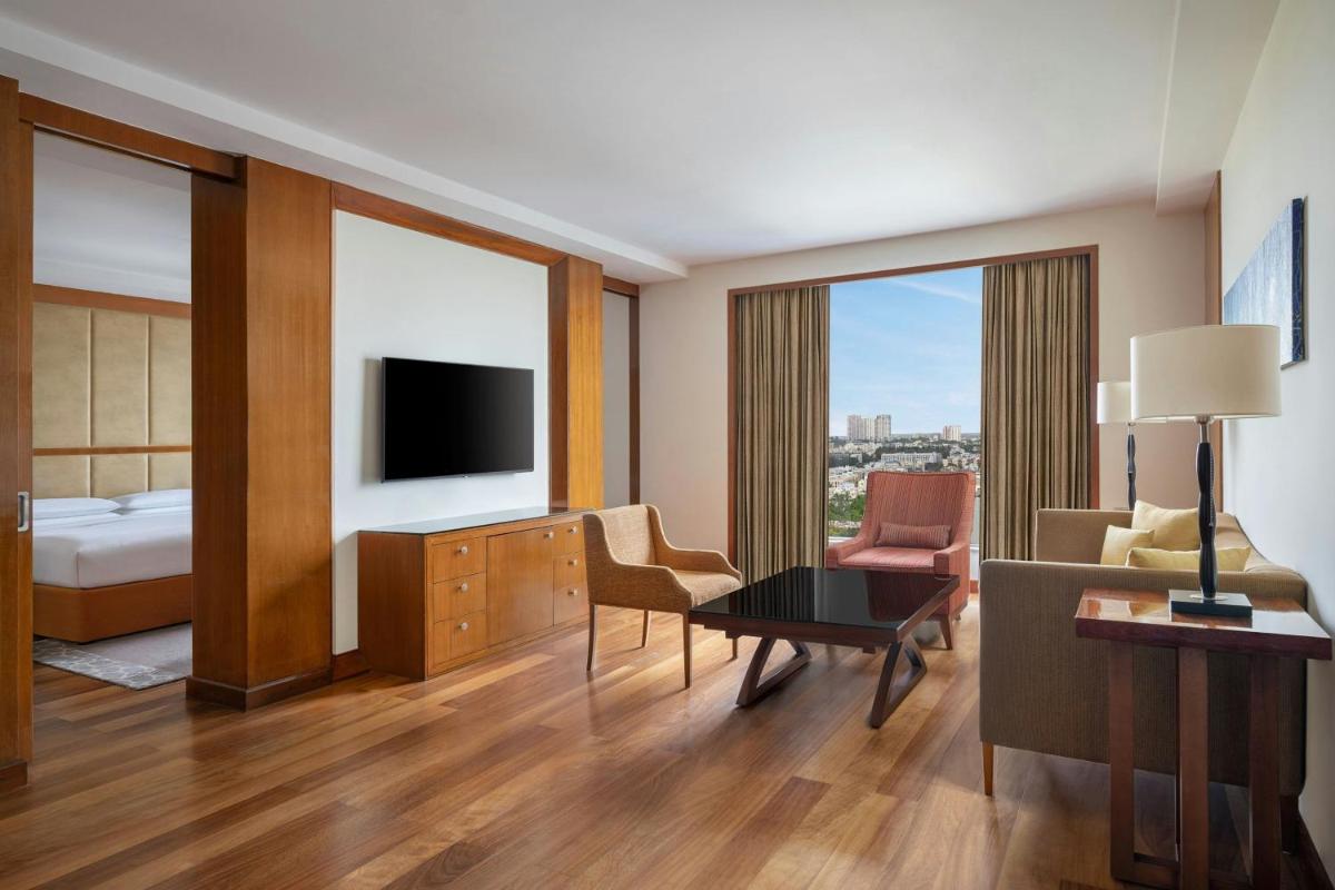 a hotel room with a bed and a living room at Bengaluru Marriott Hotel Whitefield in Bengaluru