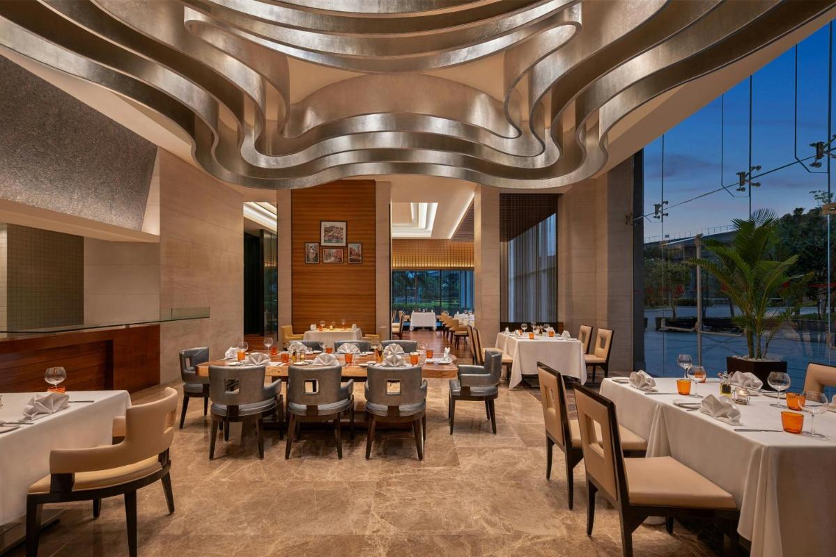 a dining room with tables and chairs and a ceiling at Bengaluru Marriott Hotel Whitefield in Bengaluru