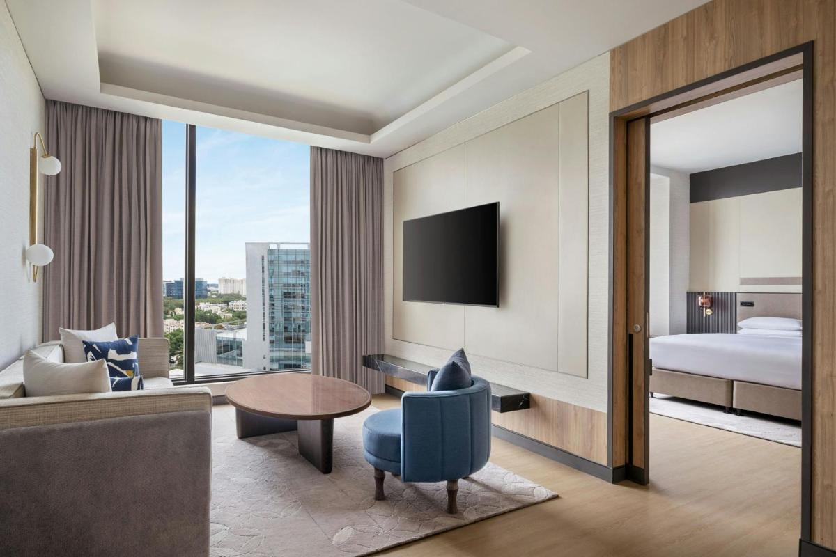 a hotel room with a king bed and a living room at Bengaluru Marriott Hotel Whitefield in Bengaluru