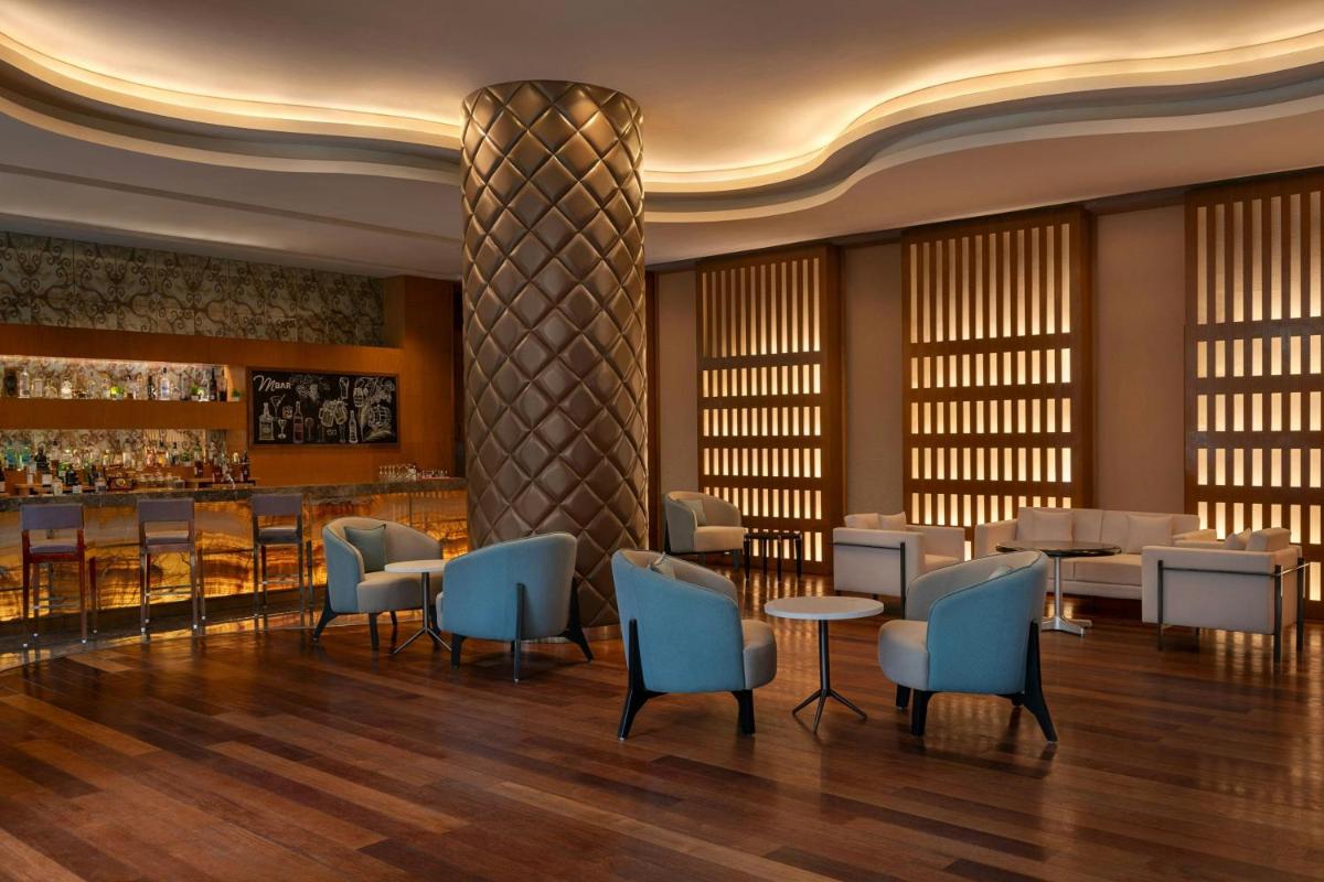 a restaurant with blue chairs and a bar at Bengaluru Marriott Hotel Whitefield in Bengaluru