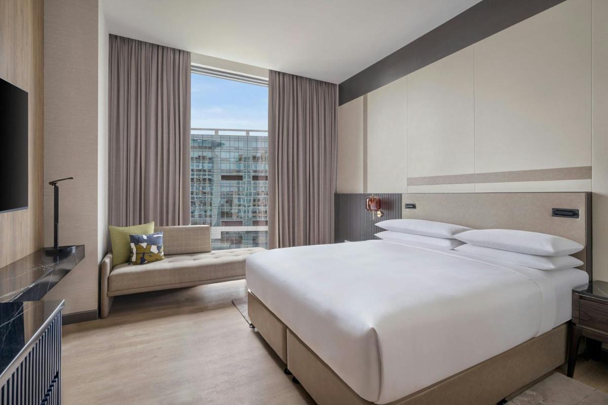 a bedroom with a large white bed and a large window at Bengaluru Marriott Hotel Whitefield in Bengaluru