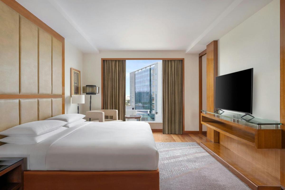 a hotel room with a bed and a television at Bengaluru Marriott Hotel Whitefield in Bengaluru