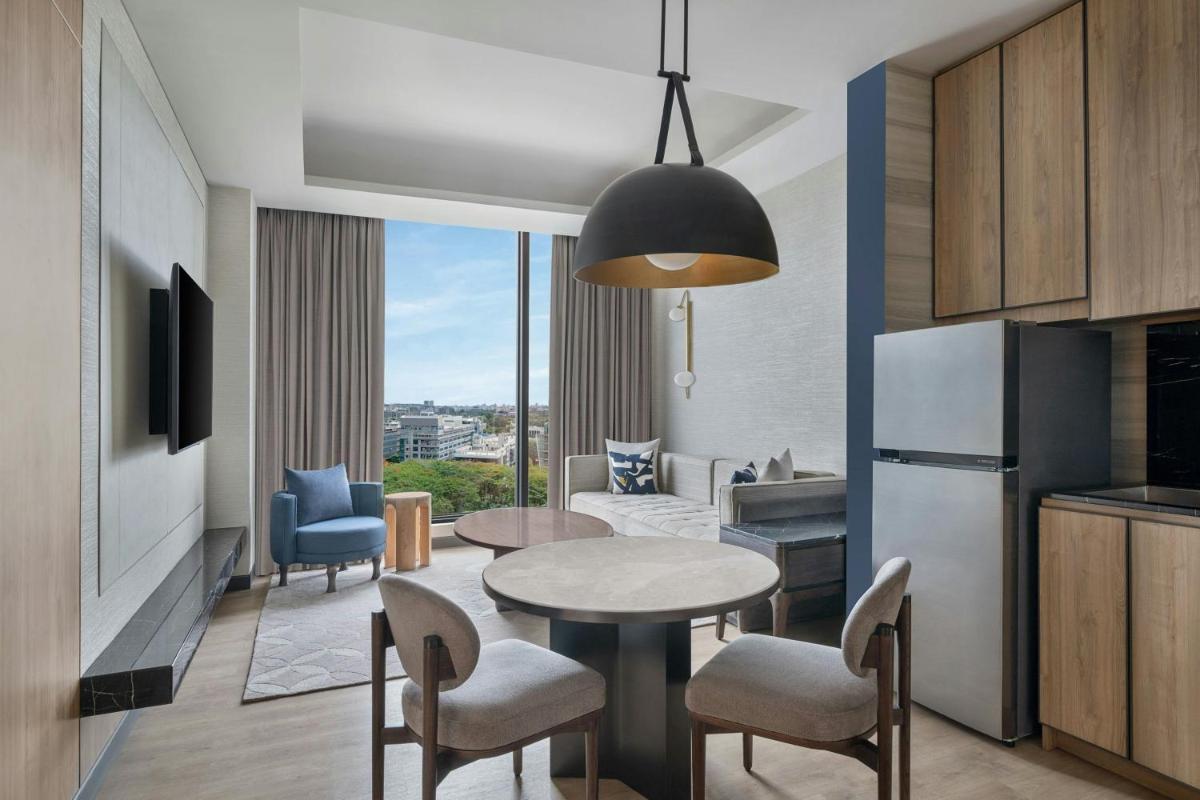 a kitchen and a living room with a table and chairs at Bengaluru Marriott Hotel Whitefield in Bengaluru