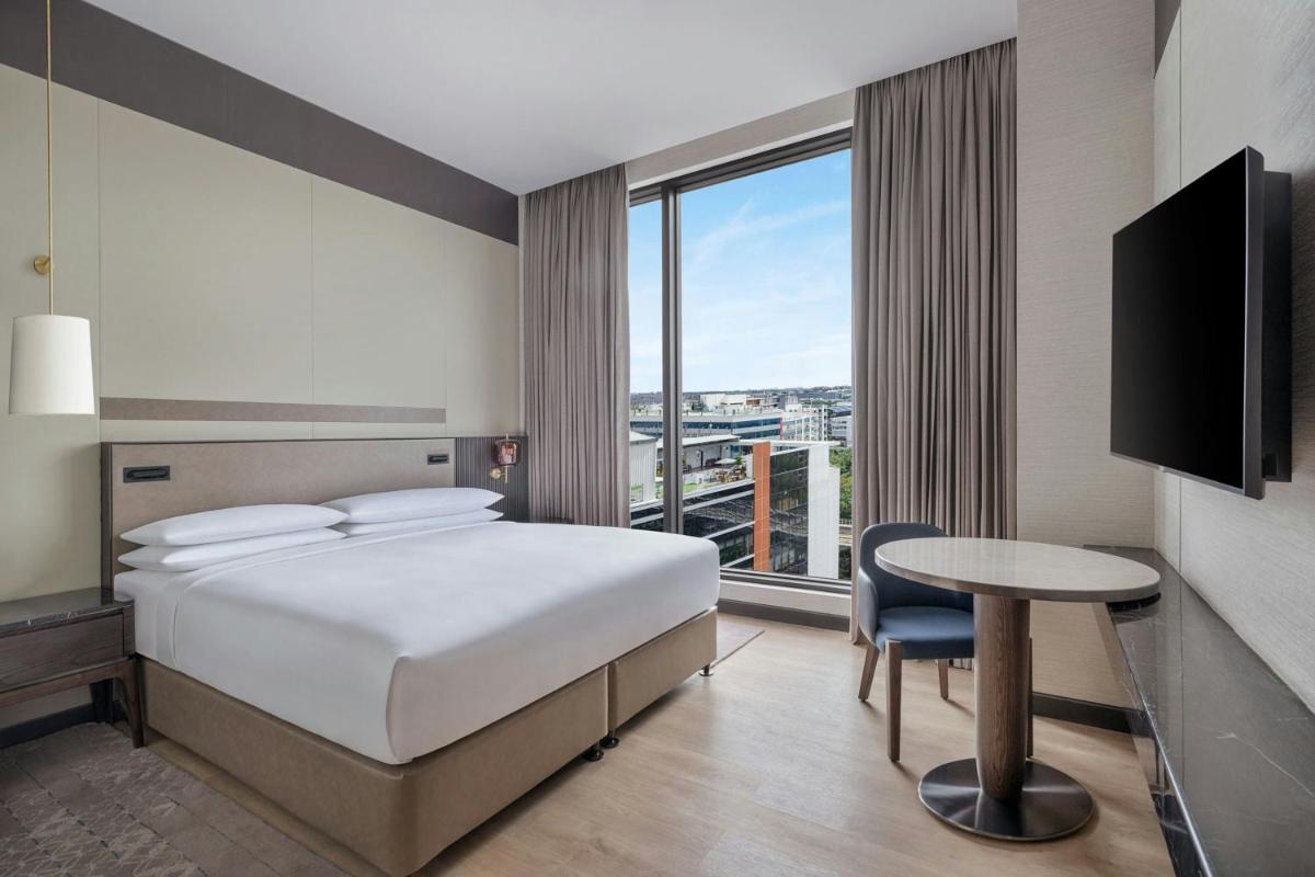 a hotel room with a bed and a table and a window at Bengaluru Marriott Hotel Whitefield in Bengaluru