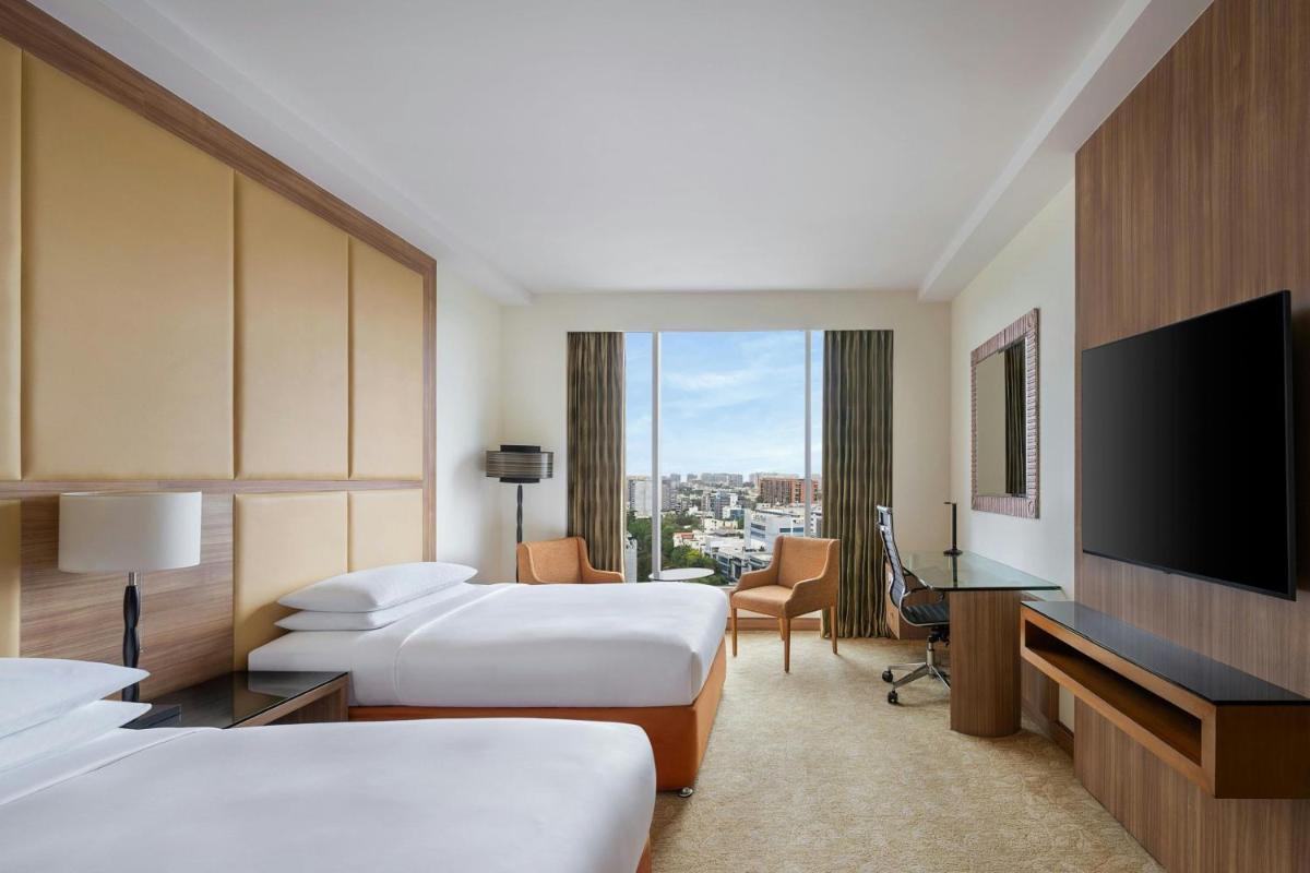 a hotel room with two beds and a flat screen tv at Bengaluru Marriott Hotel Whitefield in Bengaluru