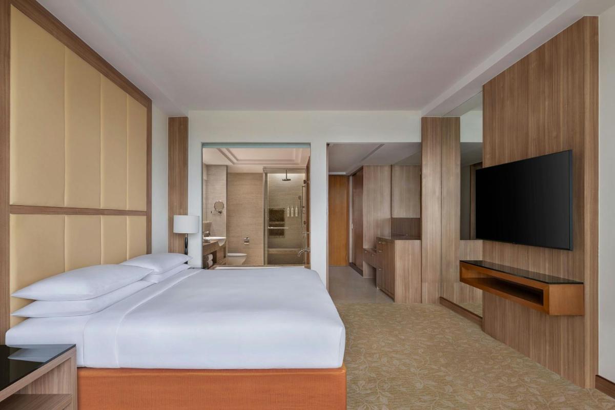 a bedroom with a bed and a flat screen tv at Bengaluru Marriott Hotel Whitefield in Bengaluru