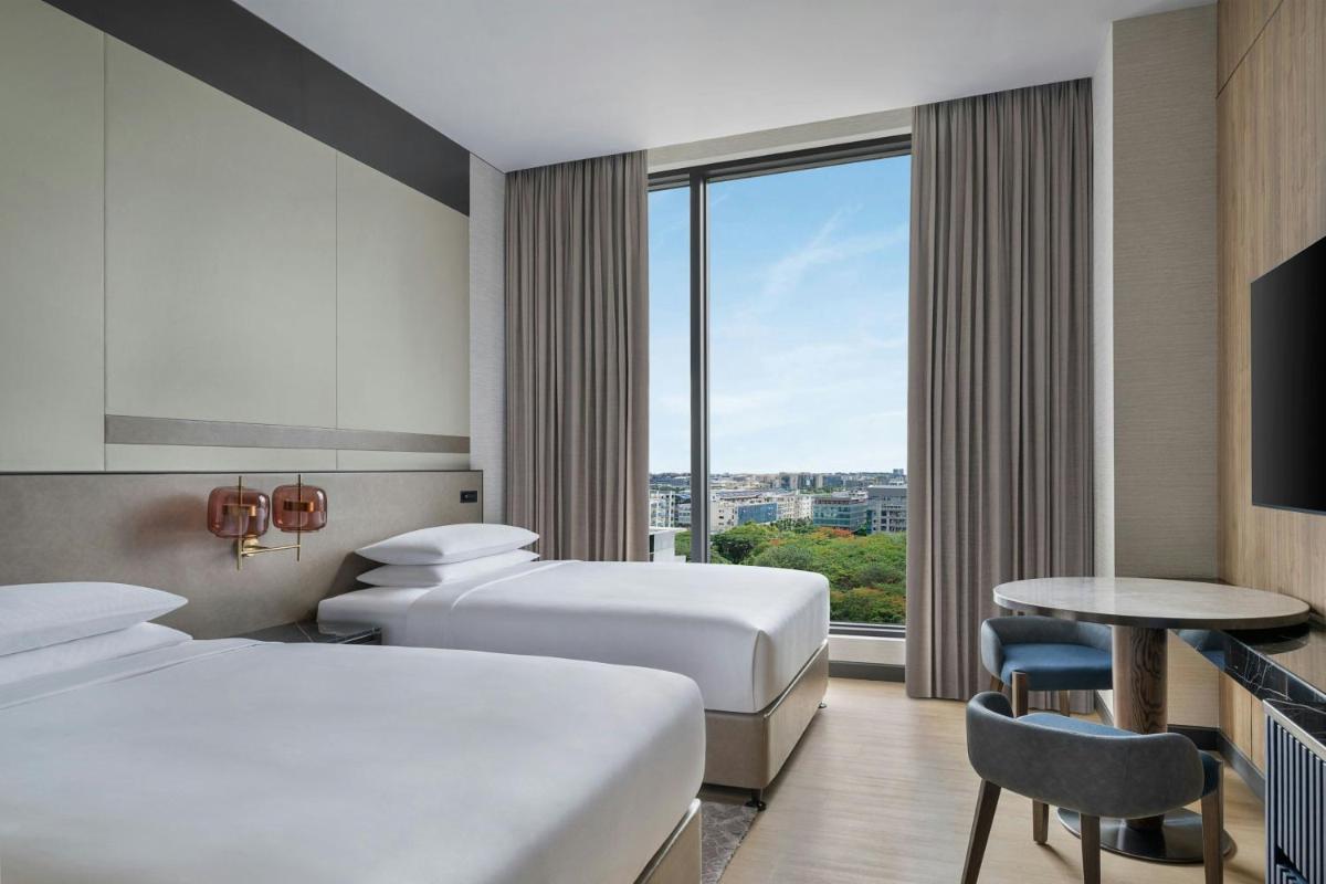 a hotel room with two beds and a window at Bengaluru Marriott Hotel Whitefield in Bengaluru