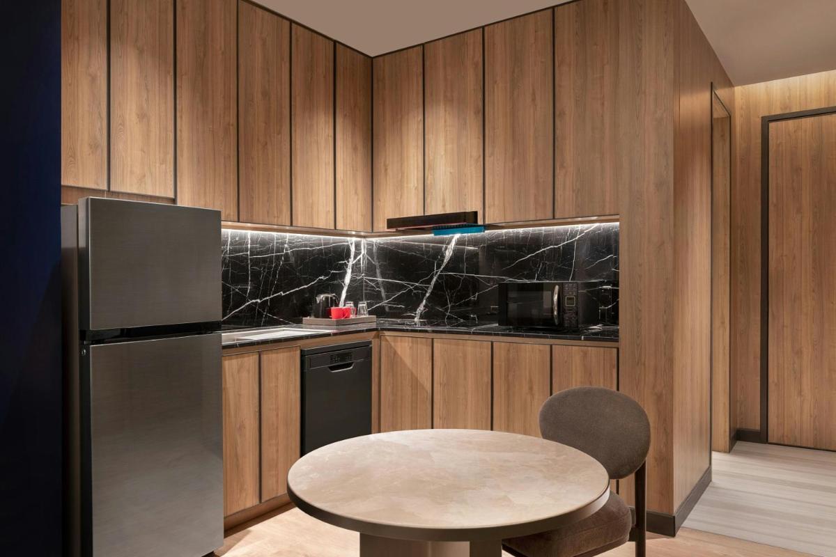 a kitchen with a table and a refrigerator at Bengaluru Marriott Hotel Whitefield in Bengaluru