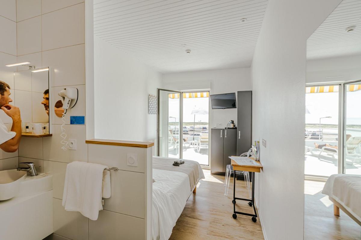 une chambre avec un lit et une salle de bain avec un lavabo dans l'établissement Hotel Les Dunes, à La Tranche-sur-Mer