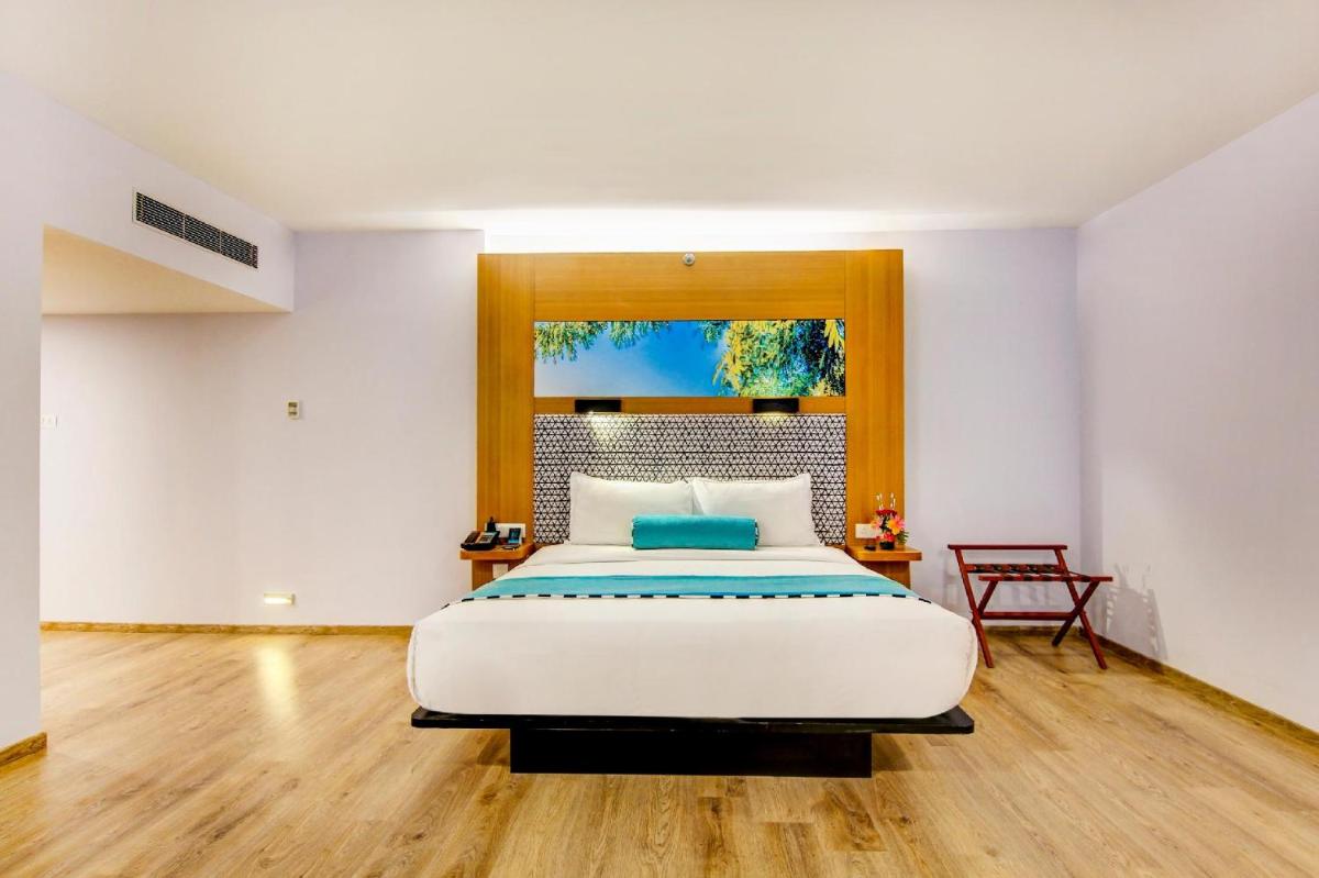 a bedroom with a large bed and a table at Sunday Hotel Chandigarh Zirakpur in Zirakpur