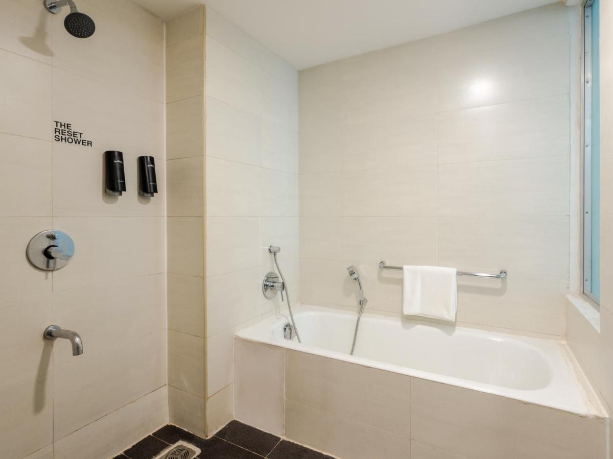 a white bathroom with a tub and a shower at Sunday Hotel Chandigarh Zirakpur in Zirakpur