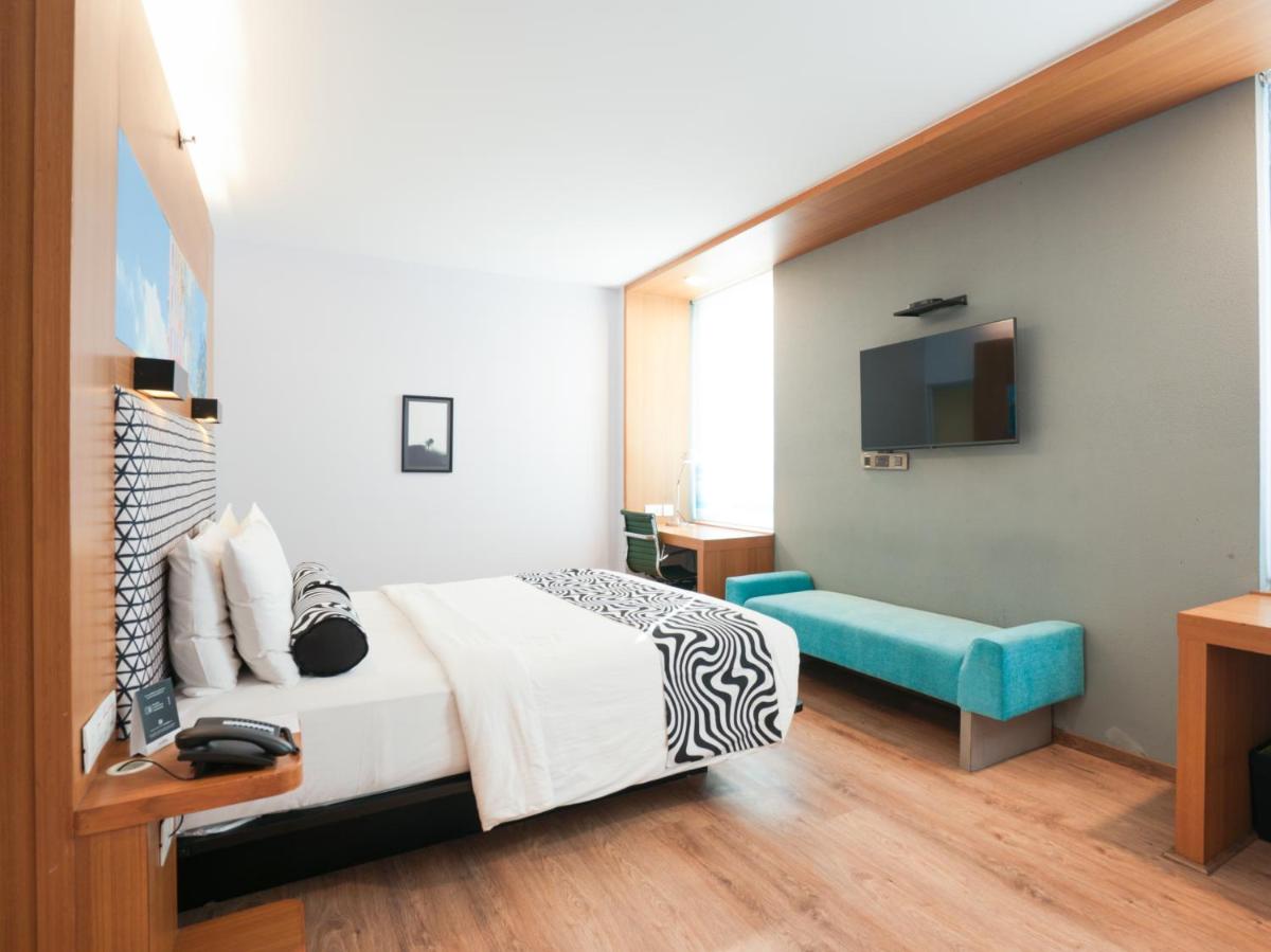 a hotel room with a bed and a tv at Sunday Hotel Chandigarh Zirakpur in Zirakpur