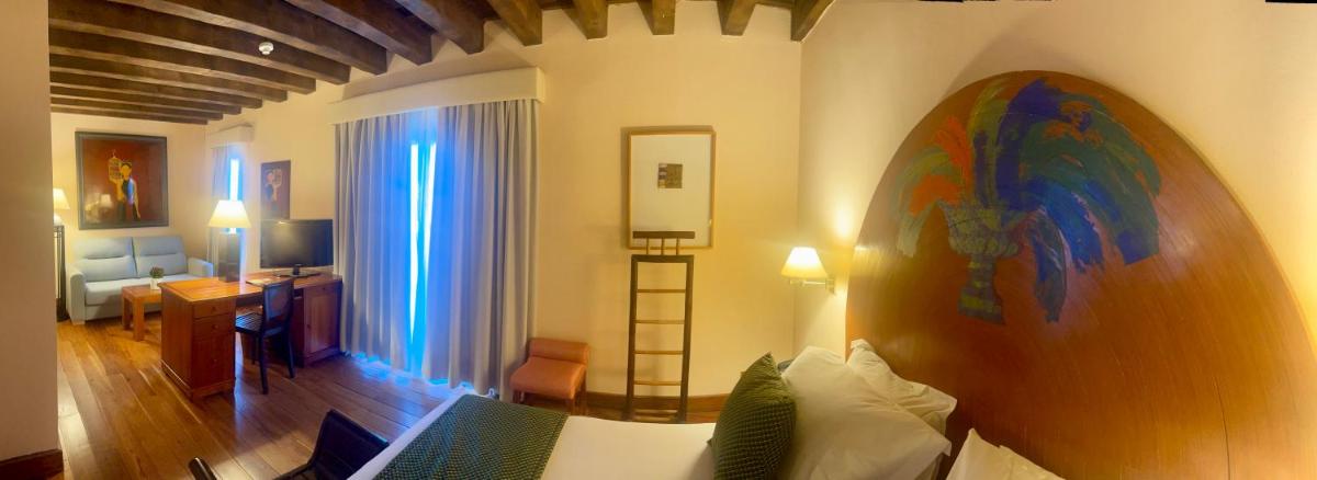 una sala de estar con sofá y una habitación con mesa en Hotel El Rancho, en Segovia