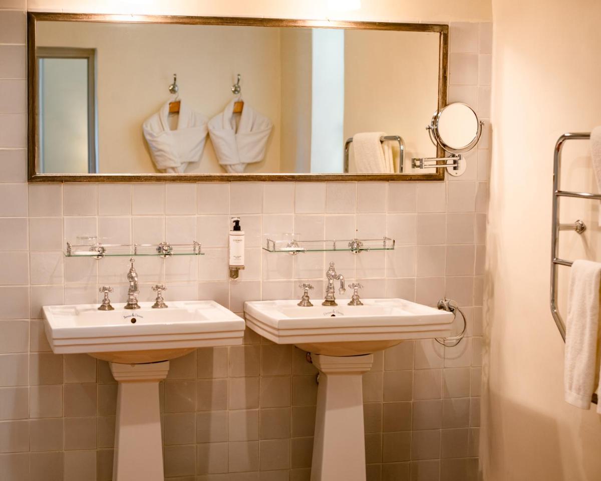 La salle de bains est pourvue de 2 lavabos, d'un miroir et de serviettes. dans l'établissement Auberge Ostapé, à Bidarray