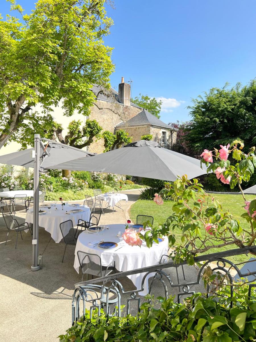 un groupe de tables et de chaises sous un parasol dans l'établissement Hôtel 4 étoiles - Restaurants & Spa Périer Du Bignon, à Laval