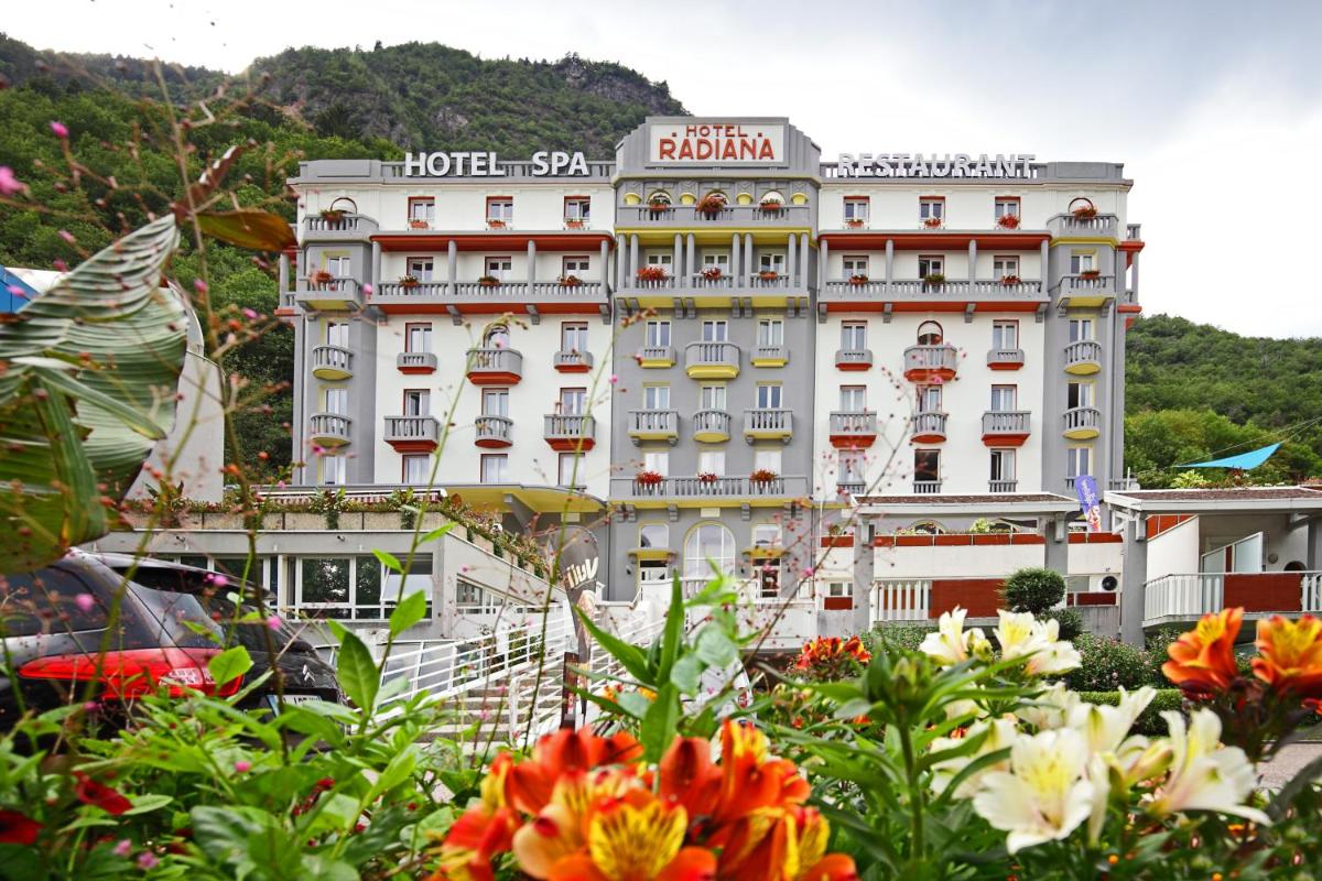 un grand bâtiment blanc avec des fleurs devant dans l'établissement Hotel & Spa Radiana, à La Léchère