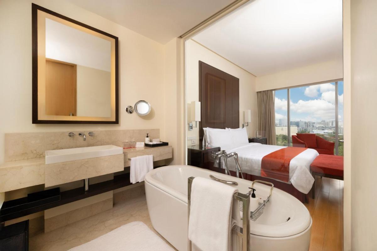a hotel bathroom with a bed and a tub and a sink at Trident Hyderabad in Hyderabad
