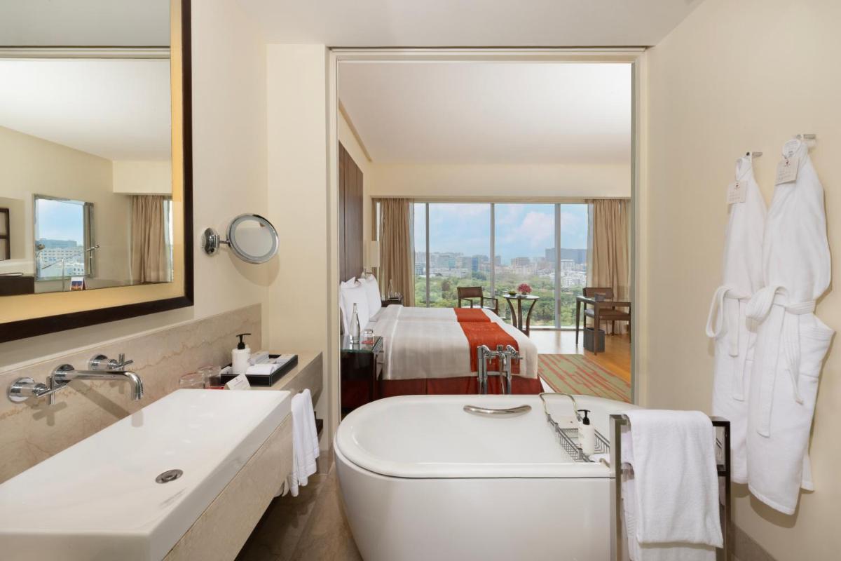 a bathroom with a tub and a sink and a bed at Trident Hyderabad in Hyderabad