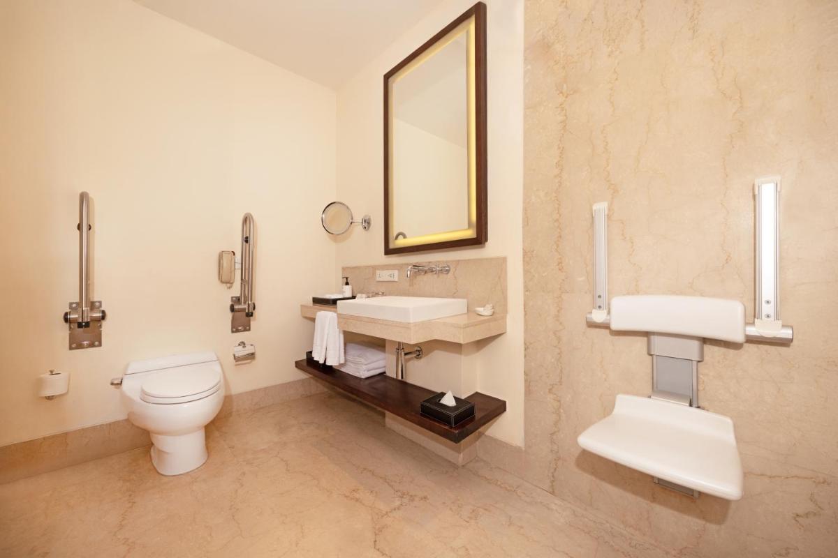 a bathroom with a toilet and a sink and a mirror at Trident Hyderabad in Hyderabad