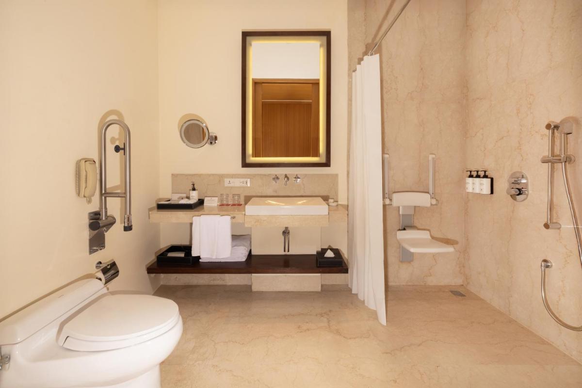 a bathroom with a toilet and a sink and a mirror at Trident Hyderabad in Hyderabad