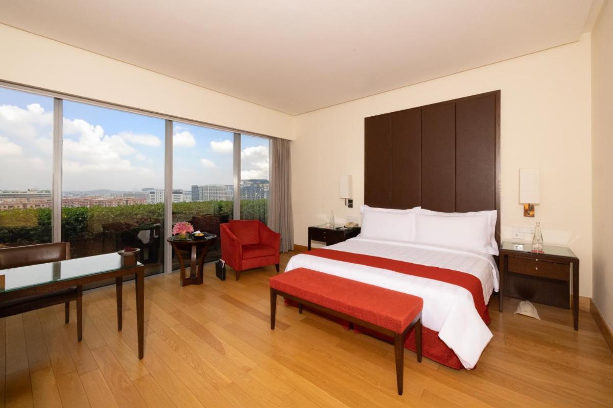 a bedroom with a large bed and a red chair at Trident Hyderabad in Hyderabad