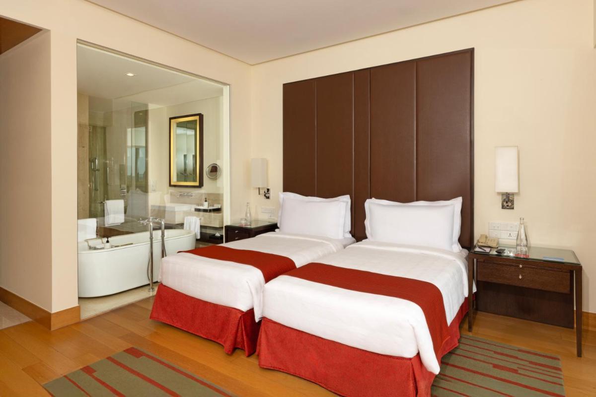 a hotel room with two beds and a bathroom at Trident Hyderabad in Hyderabad