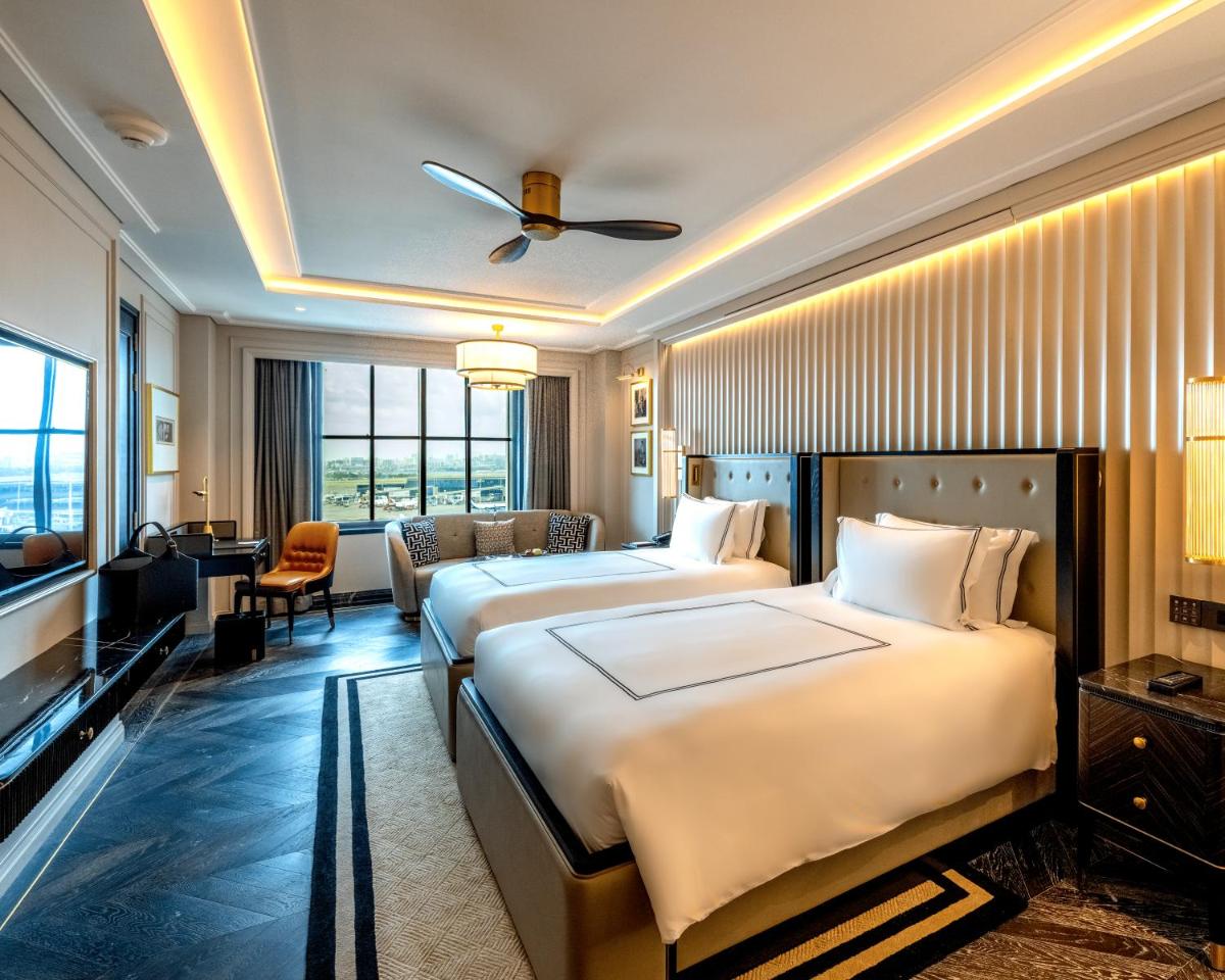 a hotel room with two beds and a television at Fairmont Mumbai in Mumbai