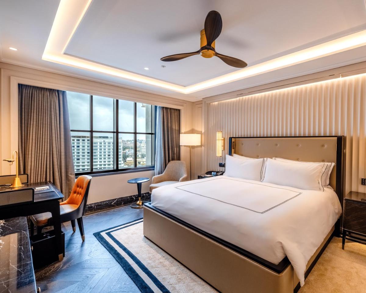 a bedroom with a bed and a desk and a piano at Fairmont Mumbai in Mumbai