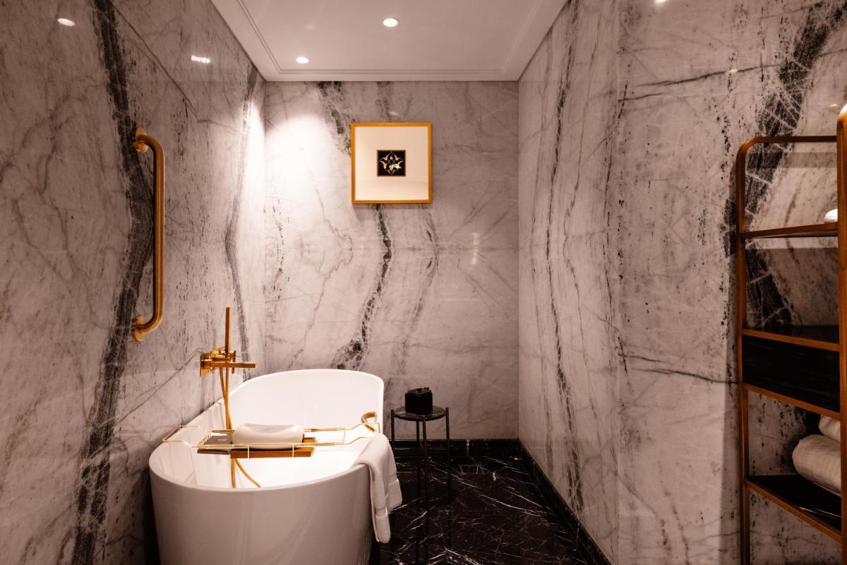 a bathroom with a white tub and marble walls at Fairmont Mumbai in Mumbai