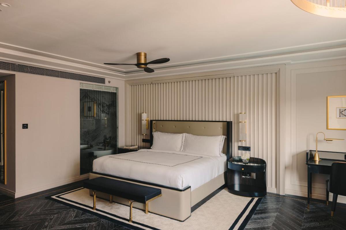 a bedroom with a white bed and a desk at Fairmont Mumbai in Mumbai