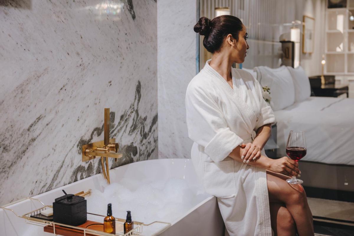 a woman sitting in a bath tub with a glass of wine at Fairmont Mumbai in Mumbai