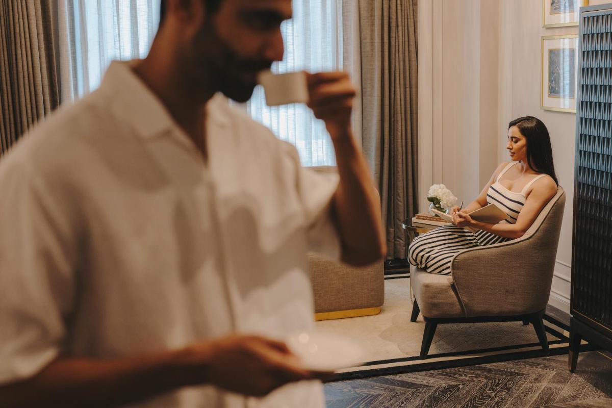a man drinking a cup of coffee in front of a woman at Fairmont Mumbai in Mumbai
