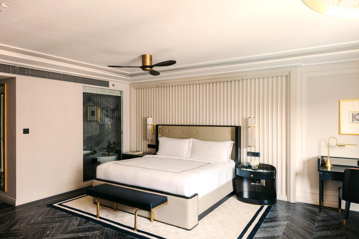 a bedroom with a white bed and a desk at Fairmont Mumbai in Mumbai